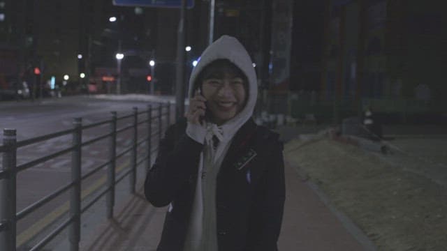 Girl walking and talking on the phone on a dimly lit street at night