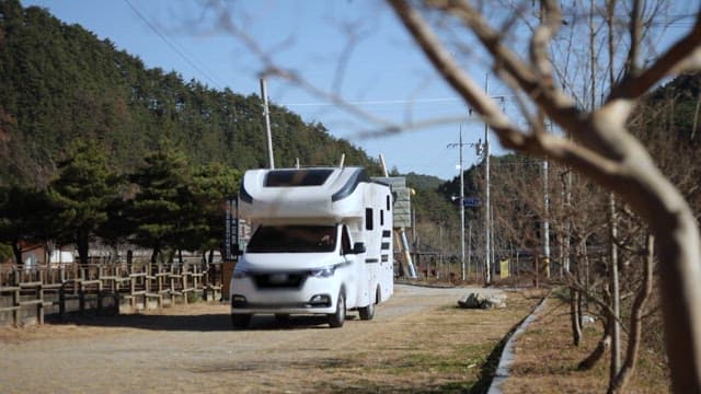 Camper Van Driving through a Country Lane with Trees and Open Sky
