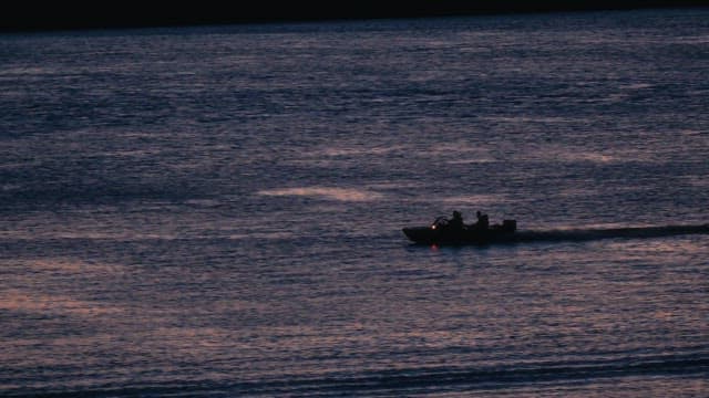 Small boat sailing across calm water at night