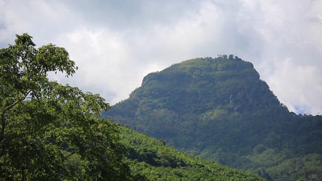Lush green mountain under a cloudy sky