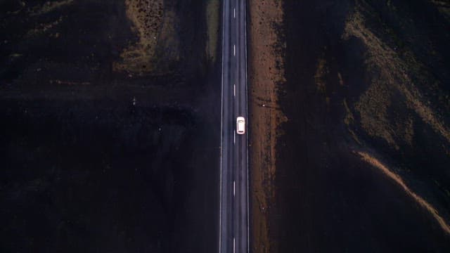 Car traveling on a road through a vast barren landscape