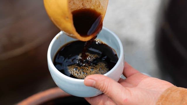 Pouring Soy Sauce from a Wooden Bowl