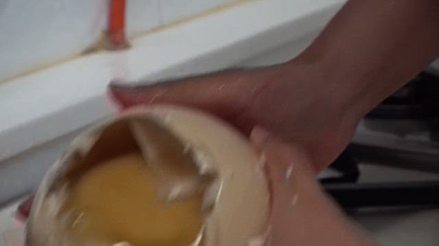 Pouring ostrich egg into a metal bowl at the kitchen sink