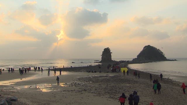 Tourists Walking Along the Mud Flats Under the Sunset Sky