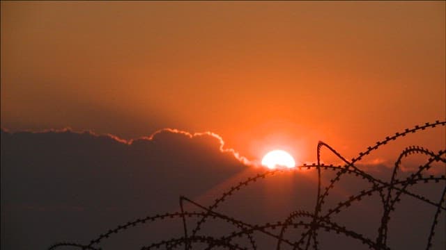 Sunset behind barbed wire on a cloudy day