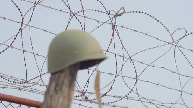 Old Military Helmet on Wooden Post with Barbed Wire