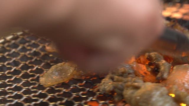 Appetizing meat grilled with tongs on a charcoal grill