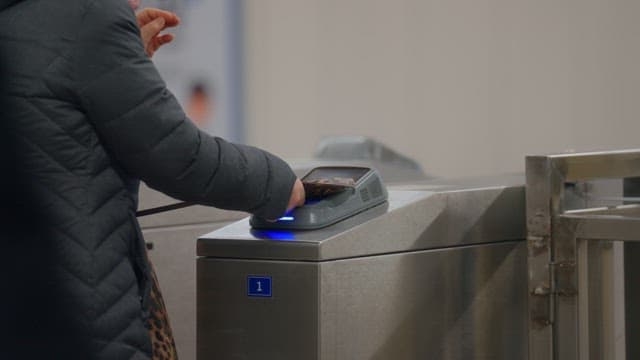 People using card readers at subway turnstiles