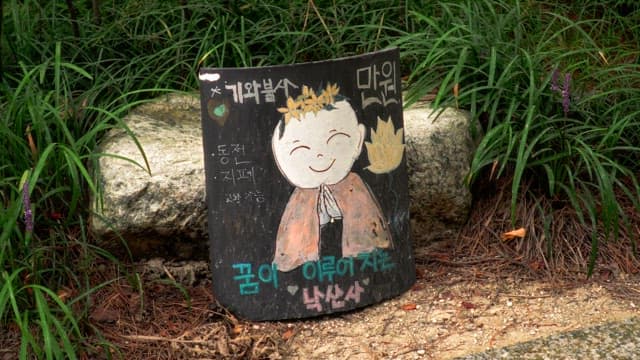 Smiling monk drawing on a signboard