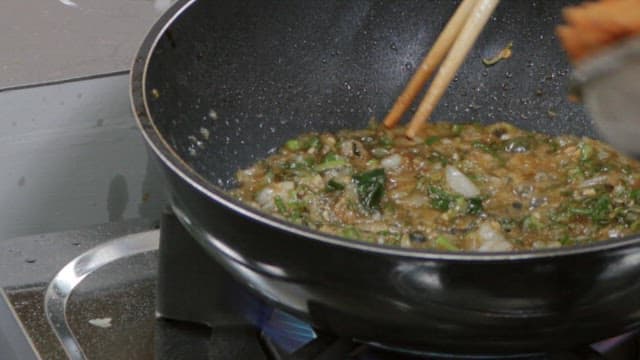 Fried fish with seasoning and vegetables stir-fried in a frying pan