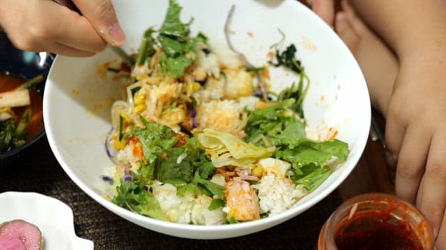 Bibimbap made by mixing fresh vegetables and gochujang with a spoon