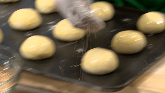 Sprinkling sesame seeds on dough balls