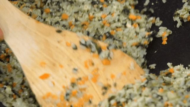 Fried rice with crab innards and chopped vegetables in a frying pan