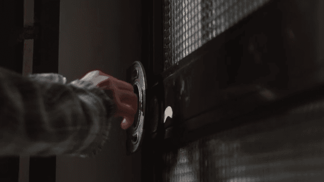 Hand stops while opening the front door of an old house