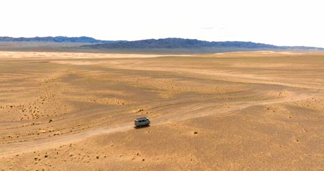 Van traveling through a vast desert