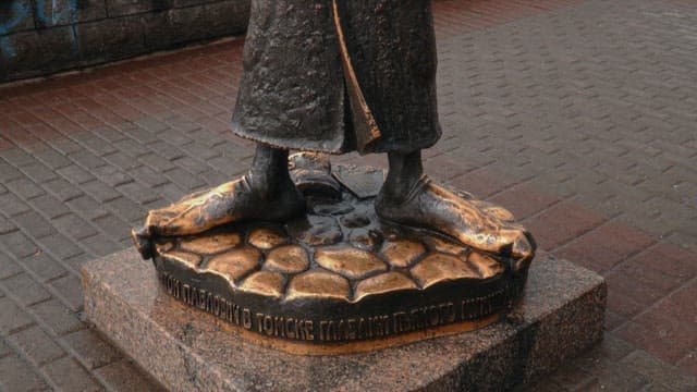 Bronze statue of Anton Chekhov with an umbrella on a riverside promenade
