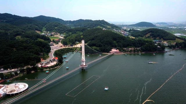 Scenic view of a mountainous landscape with a prominent bridge over a river on a sunny day.
