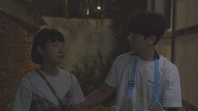 Woman and a man with arm casts walking down an alley at night