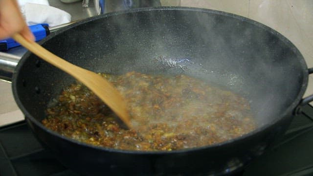Frying green onions in oil and seasoning them with red pepper powder
