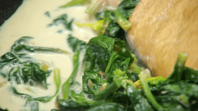 Stir-frying spinach with milk using a wooden spatula
