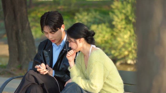 Couple sharing earphones on a park bench