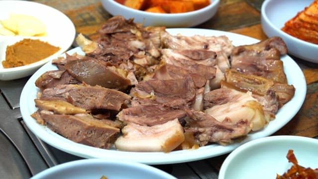Plate of sliced boiled meat with side dishes