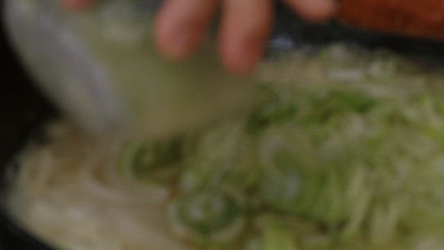Stir-frying green onions with radish in a frying pan
