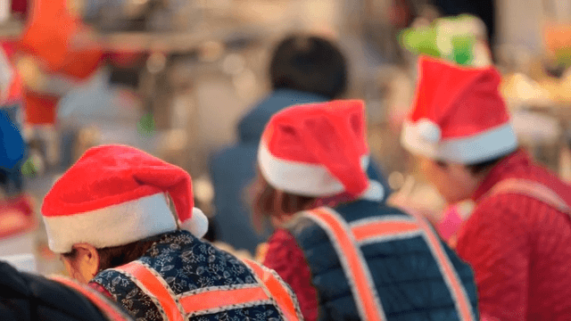 Women wearing santa hats eating food sitting in the market