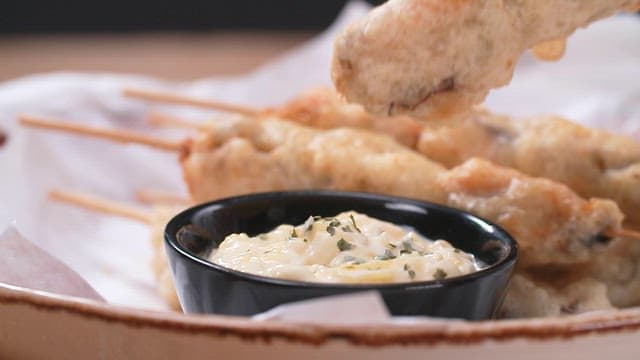 Dipping skewered fried mussels in creamy dipping sauce