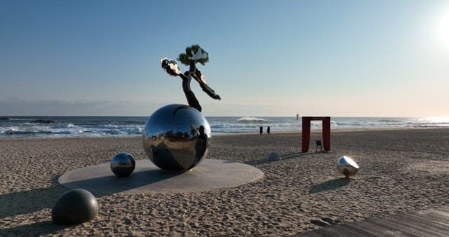 Serene Beach with Sculptures and Visitors on a Sunny Day