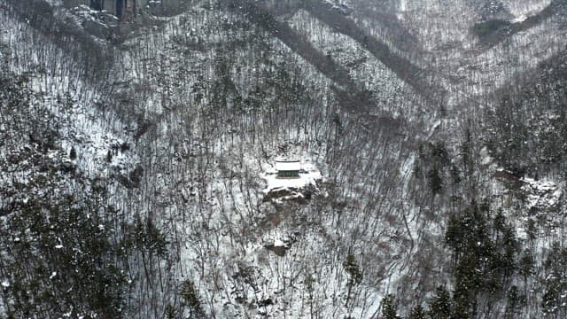 View of a snowy temple in the forested hills