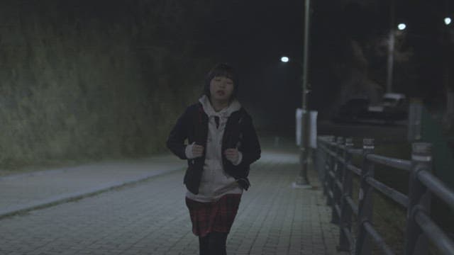 Girl walking alone on a dimly lit street at night