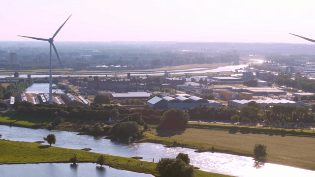 Wind turbines near a river and industrial area