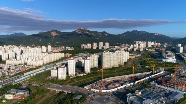 Cityscape with Construction Sites and Green Mountains