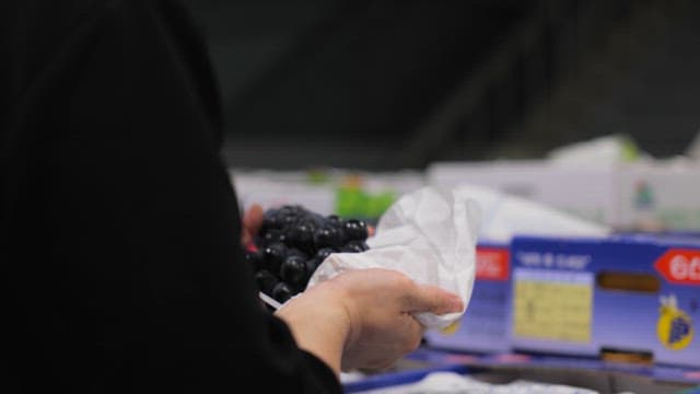 Person handling grapes in a market