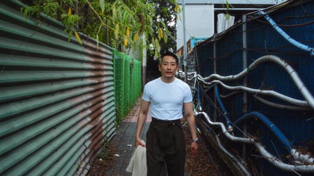 Man touching his head while walking down an alley