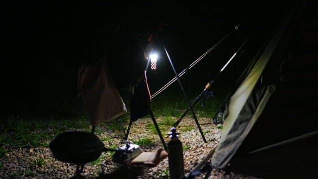 Cozy night camping scene with lantern and equipment