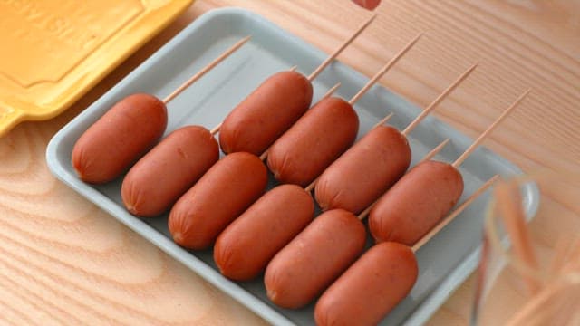 Sausages on skewers arranged on a tray