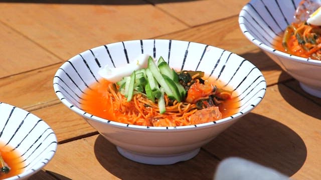 Spicy young summer radish kimchi noodles with cucumber slices