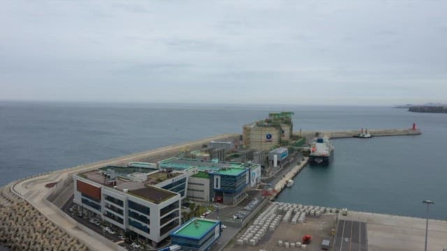 Industrial facility near the sea with large storage tanks and docking stations