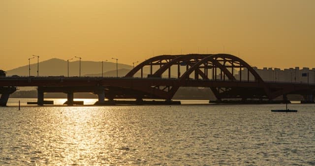 Sunset progression over an urban bridge reflected in the water