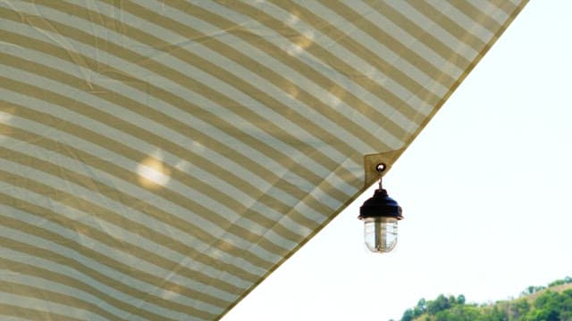 Outdoor lamp hanging under striped canopy