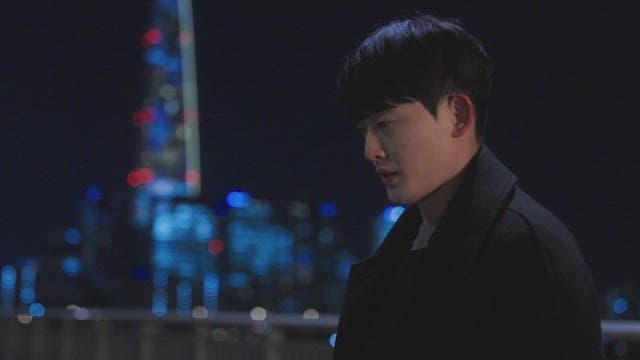 Pensive man standing by the railing with city lights at nigjht