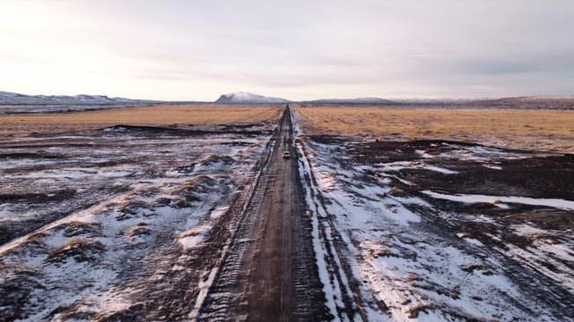 Car driving on a snowy road in open fields