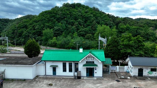 Small countryside train station nestled in lush green hills under a cloudy sky