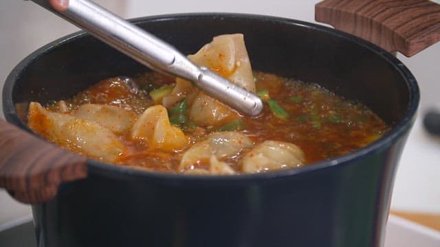 Boiling dumplings in spicy soup with tongs