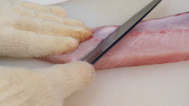 Slicing fresh yellow tail on a cutting board
