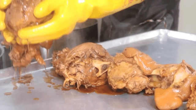 Cooking process of simmered pig's feet with gloved hands