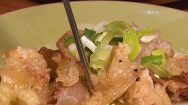 Person picking up fried meat with chopsticks
