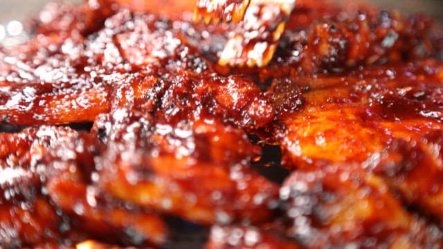 Marinated meat sizzling on a grill over blazing charcoal